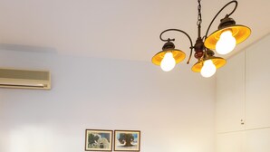 Een hotelkamer met een bed, twee bedlampen, een plafondlamp en twee ingelijste foto's aan de muur.