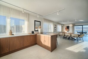 Une cuisine moderne dotée d’un grand îlot central, d’un coin repas avec des chaises et de grandes fenêtres.