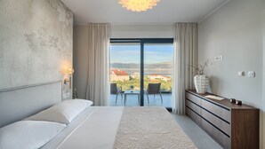 Een slaapkamer met een groot bed, een kapstok, een nachtkastje, een raam met uitzicht en een hanglamp.