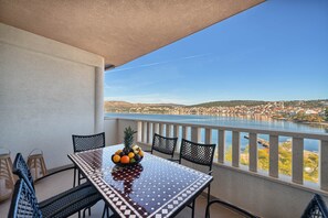 A balcony with a table, chairs, and a fruit bowl. - Aurore's Place - Cozy Seaview Apartment (Okrug Gornji)