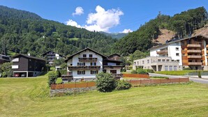 Un quartier résidentiel avec des maisons, un champ verdoyant et une chaîne de montagnes en arrière-plan.