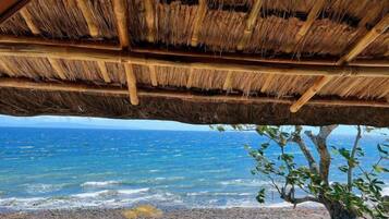 A thatched roof structure with a view of the ocean.