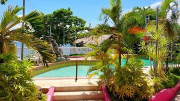 A pool surrounded by tropical plants and a staircase leading to a higher level.