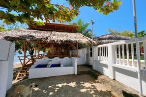 A thatched-roof outdoor seating area with white railings and a view of the beach. - AoJing Diving Resort (Dauin)