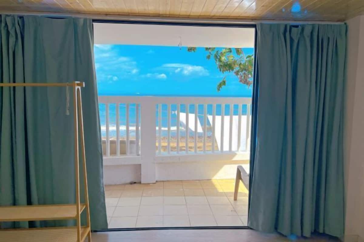 A room with a view of a white balcony and a clear blue sky.