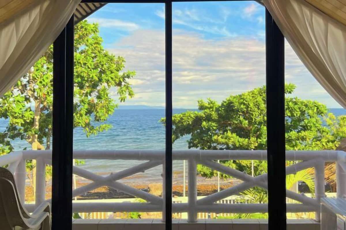 A view from a balcony with a railing, overlooking a body of water and greenery.