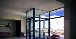 Eine Lobby mit Glastür, einem violetten Sofa und einer Wand mit runden Spiegeln.