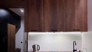 A modern kitchen with wooden cabinets, a stainless steel kettle, and a black faucet. - Mountain Serenity — 5 min. to the ski lift (New Gudauri)