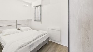 Ett modernt sovrum med en säng, ett fönster med gardiner och ett väggmonterat element.