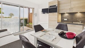 Ett modernt kök med inbyggd ugn och mikrovågsugn, en matplats med ett bord för två personer och en skjutdörr i glas som leder ut till en uteplats.