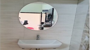 Un baño con un espejo redondo, un lavamanos blanco y un perchero para toallas.