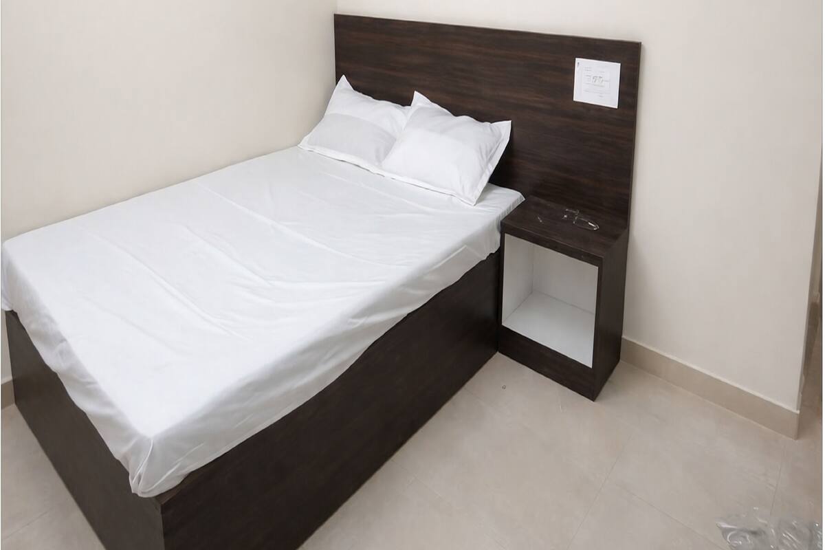 Una cama individual con cabecera de madera y mesita de noche.