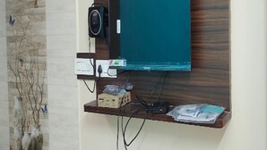 Televisor montado en la pared sobre un panel de madera, con una regleta y cables.