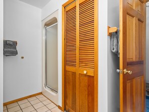 A bathroom with a shower, a wooden door, and a towel rack.