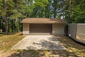 A single-story building with a garage door, a covered driveway, and a trailer parked beside it.
