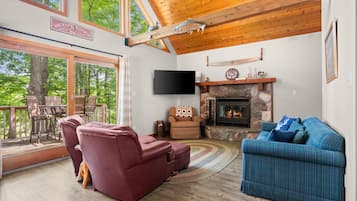 Un salon spacieux doté d’une cheminée, de sièges confortables et de grandes fenêtres offrant une vue sur l’extérieur.