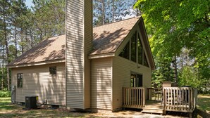 A single-story cabin with a chimney, a small porch, and a wooden deck.