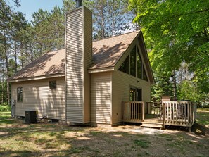 A single-story cabin with a chimney, a small porch, and a wooden deck.