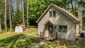 A single-story house with a front porch, a small shed, and a chimney.