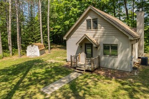 A single-story house with a front porch, a small shed, and a chimney.