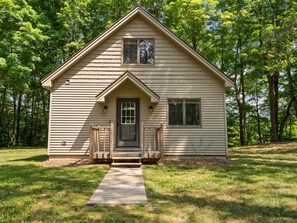 A small, single-story wooden cabin with a front porch, a door, and a window.