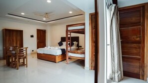 A bedroom with a wooden bed, a ceiling fan, and a wooden wardrobe. - Sayora Hotels (Port Blair)