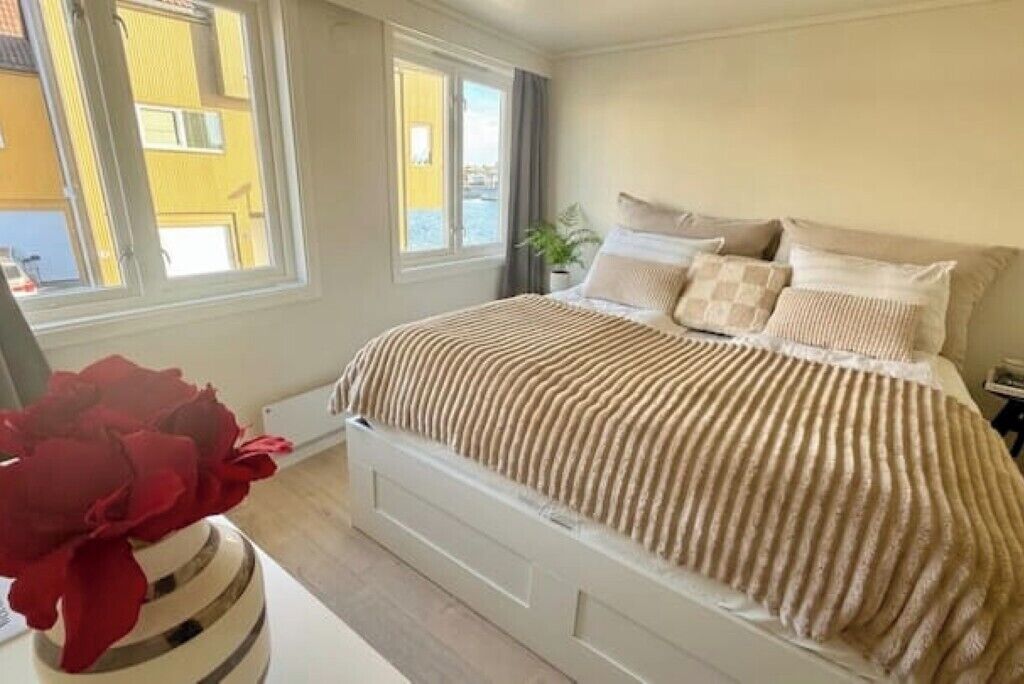 A bedroom with a bed, a window, and a potted plant.
