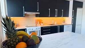 Una cucina con pensili scuri, un piano di lavoro in marmo e una ciotola di frutta.