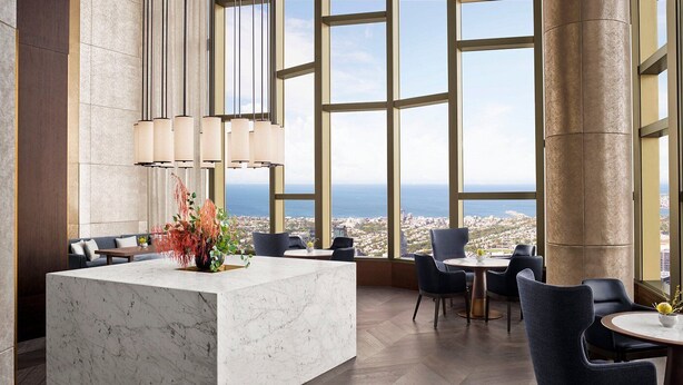 Een moderne hotellobby met een marmeren receptiebalie, grote ramen met uitzicht op de stad en modern meubilair.