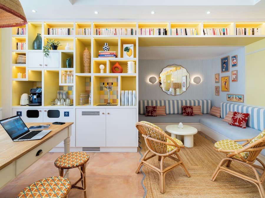 Una sala de estar moderna con un sofá, sillas, una mesa de centro, una estantería y un ordenador portátil sobre un escritorio.