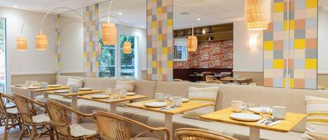 A restaurant with wooden furniture, a colorful wall, and hanging lights.