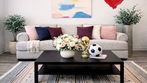 Ein Wohnzimmer mit einer Couch, einem Couchtisch mit Blumenvase, einem Fußball und einer Trophäe.