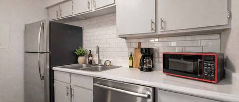 Une cuisine moderne équipée d’appareils électroménagers en acier inoxydable, d’un lave-vaisselle et d’un four à micro-ondes.