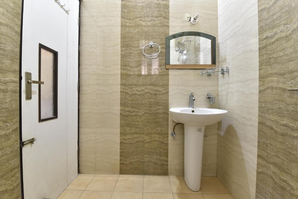 Une salle de bain avec un lavabo blanc, un miroir et un porte-serviette fixé au mur.