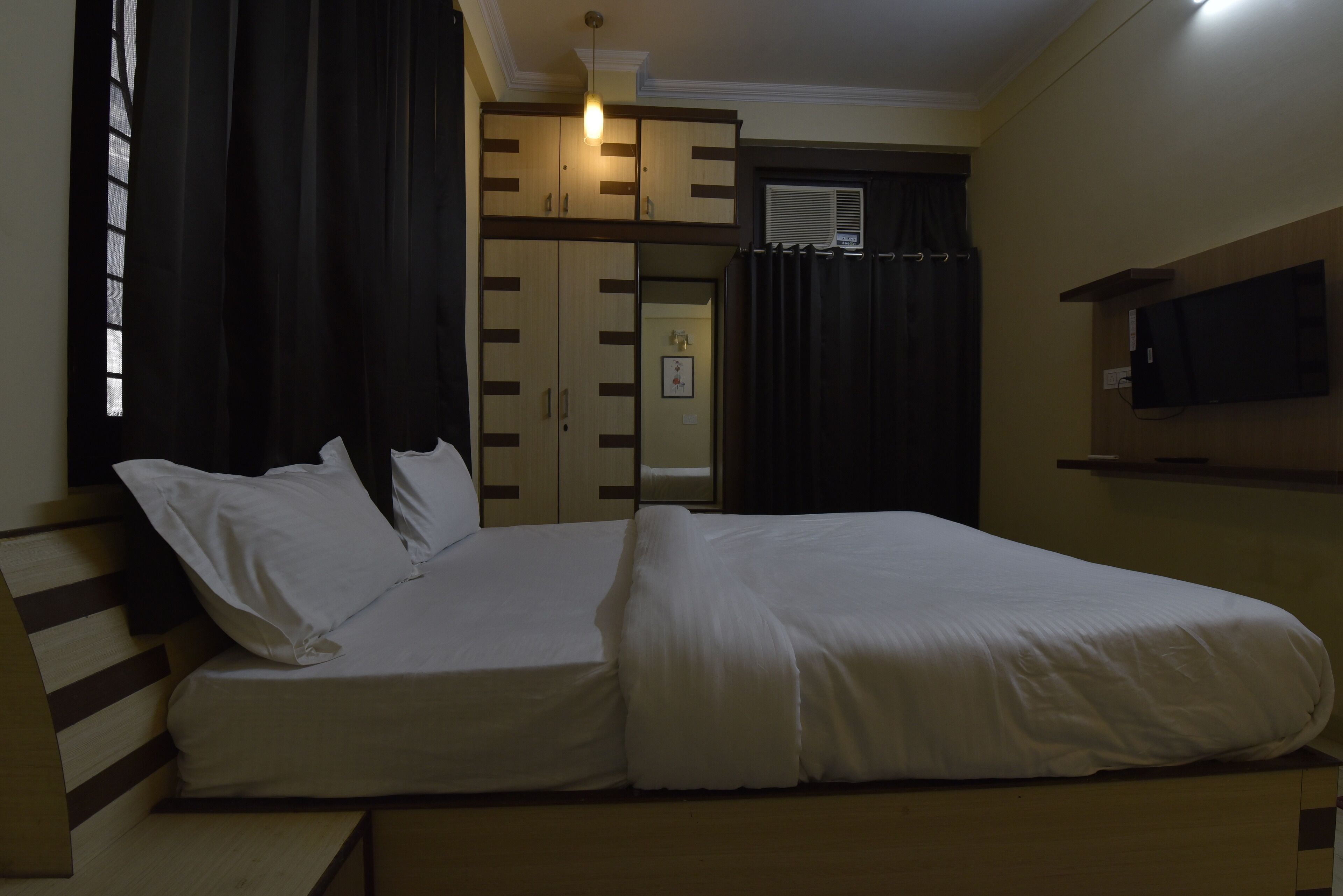 A bedroom with a bed, a wardrobe, and a TV.