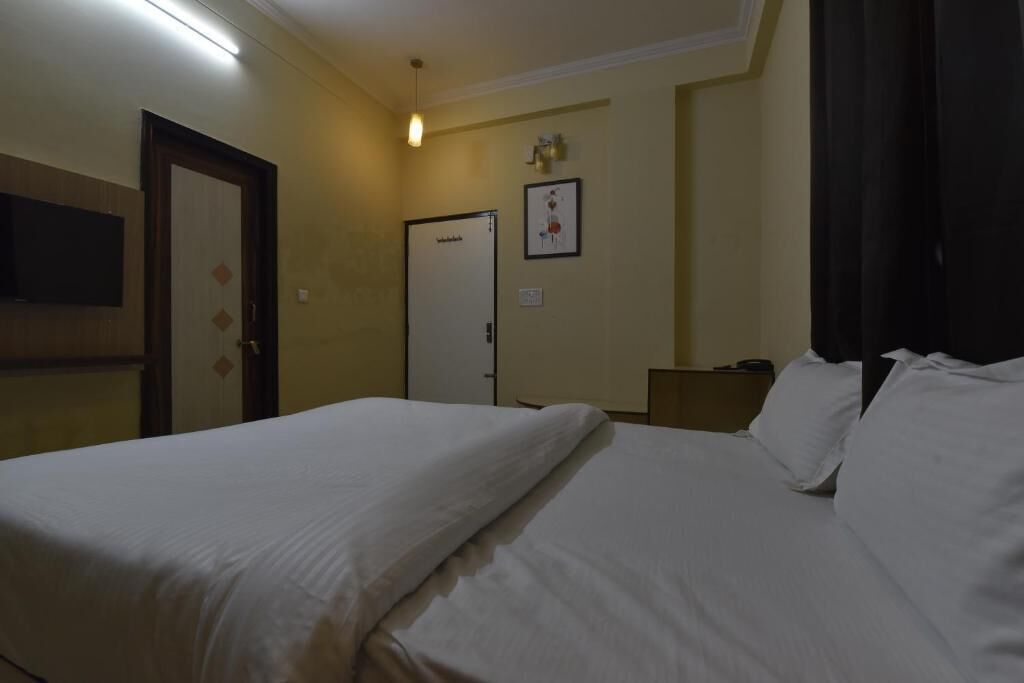 Habitación de hotel con dos camas, un televisor montado en la pared y una puerta con picaporte decorativo.