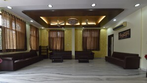 A spacious room with a marble floor, two sofas, a coffee table, a ceiling fan, and a chandelier. - Hotel The Grand Kailash (Jaipur)