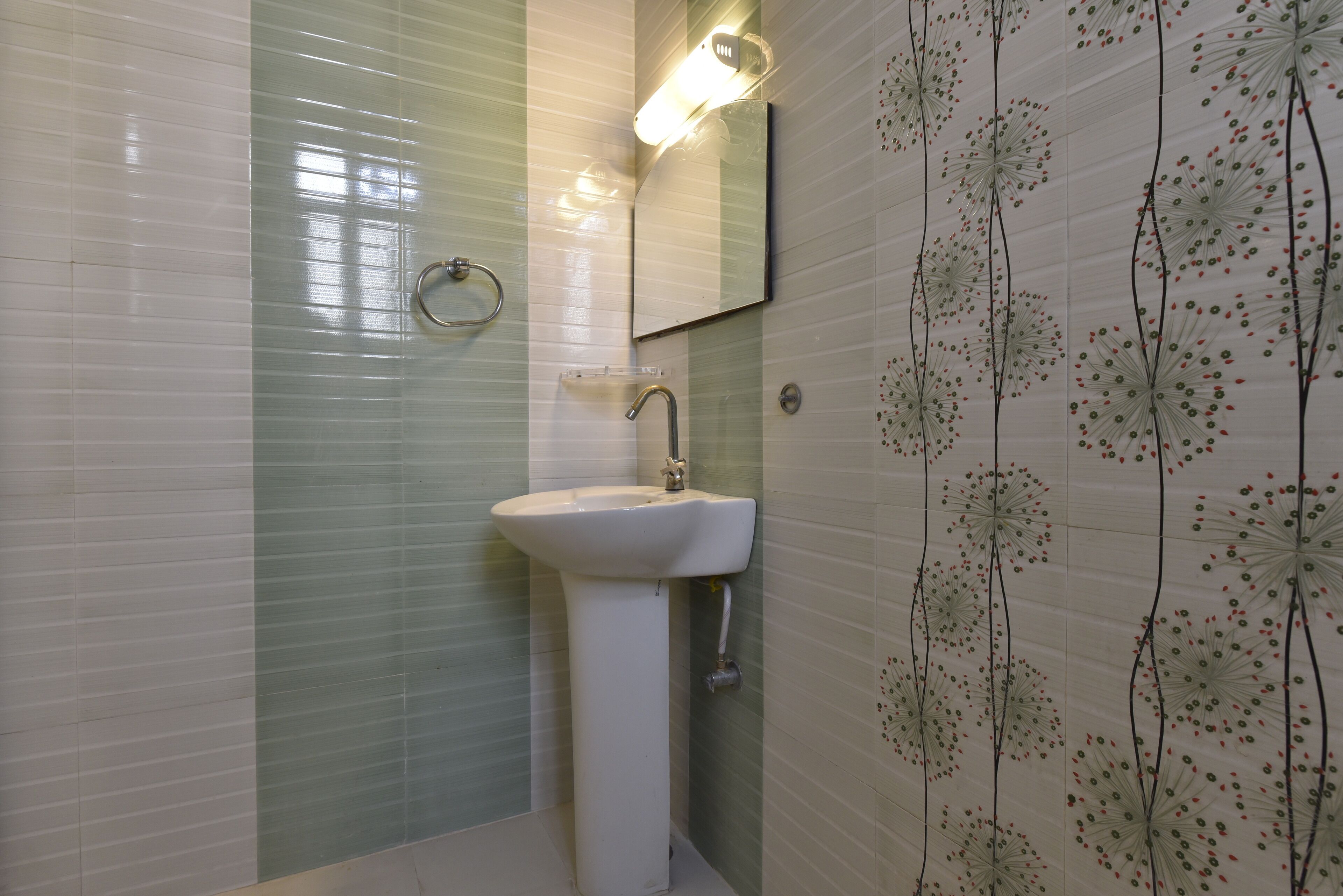Een badkamer met een witte wastafel, een spiegel en een wand met een bloemenmotief.