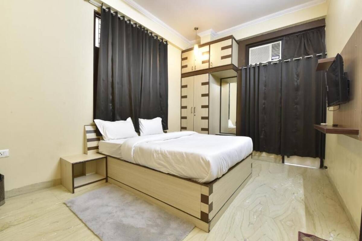 A bedroom with a bed, a small bedside table, a built-in wardrobe, and a television mounted on the wall.