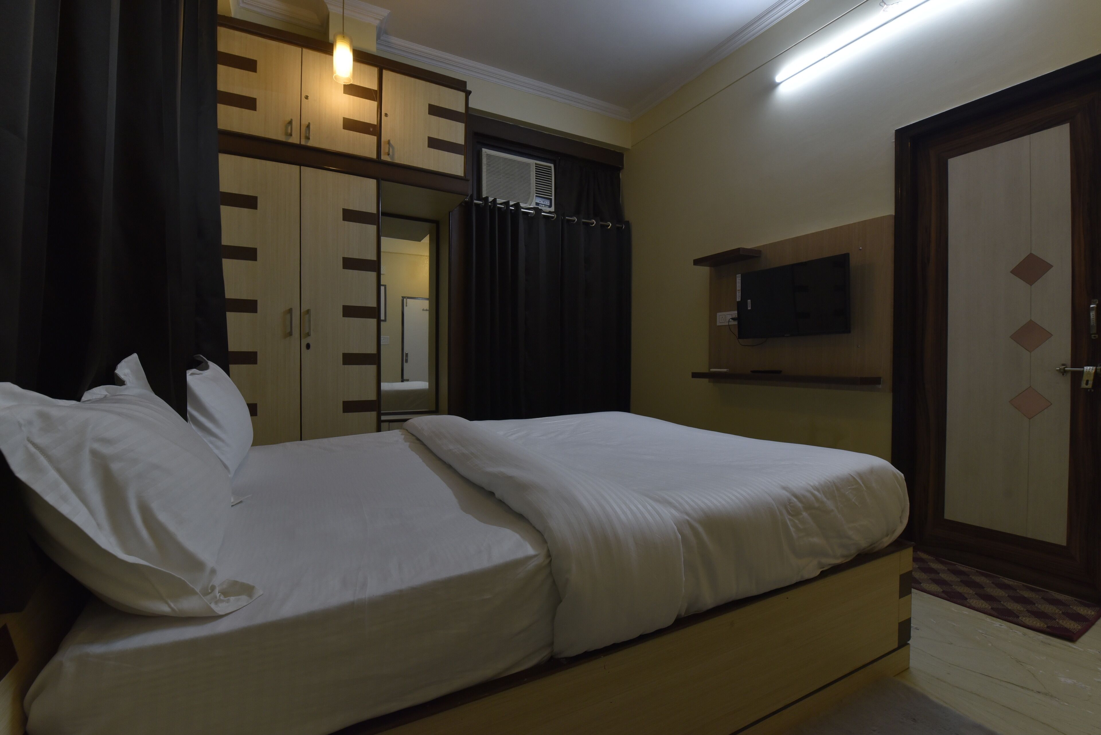 Un dormitorio con cama doble, televisión montada en la pared y armario con espejo.