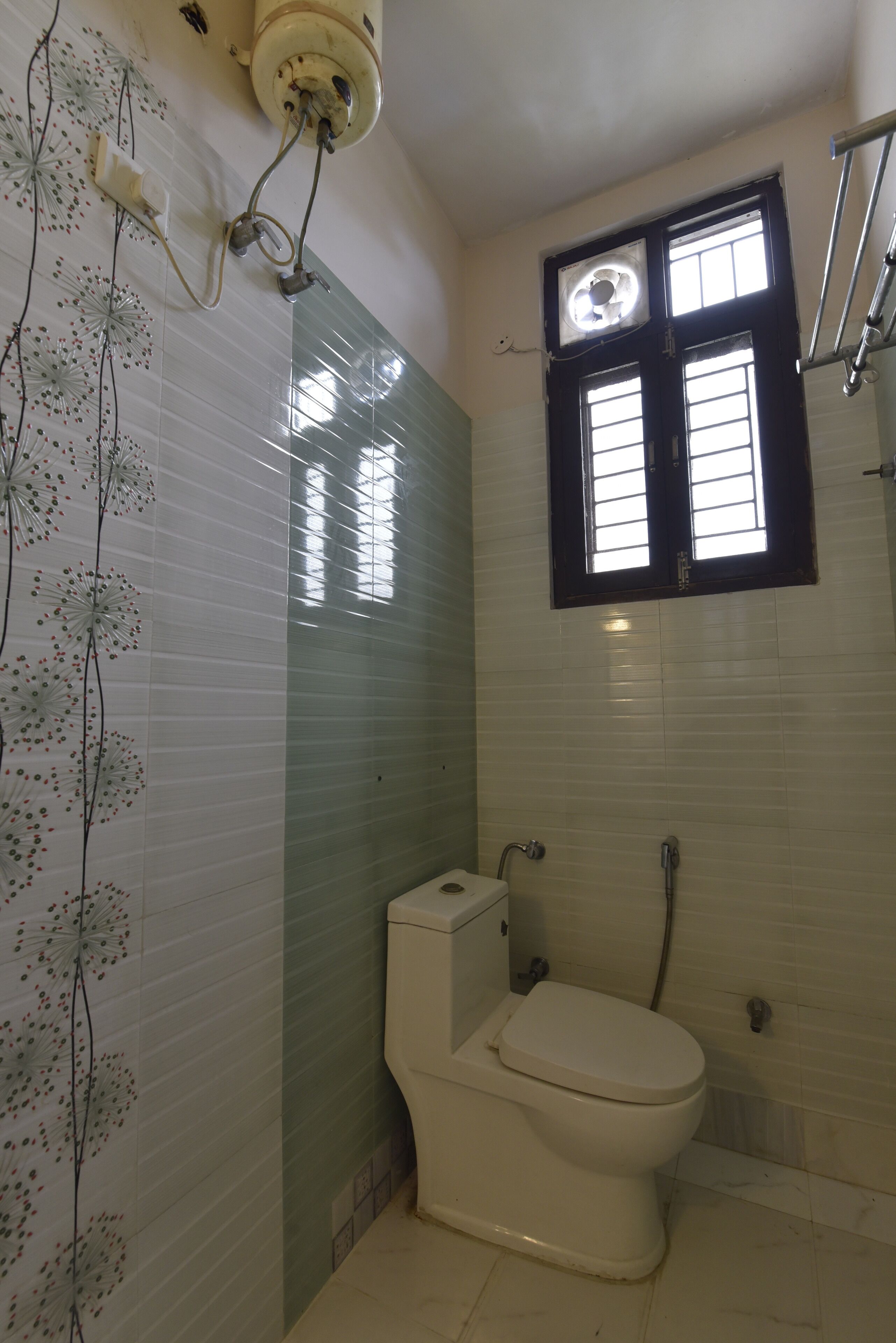 A bathroom with a toilet, a window, and a shower area.