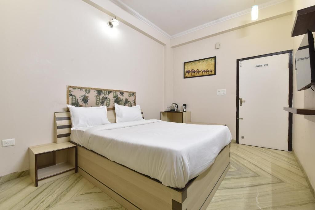 A bedroom with a bed, bedside table, nightstand, and a door.