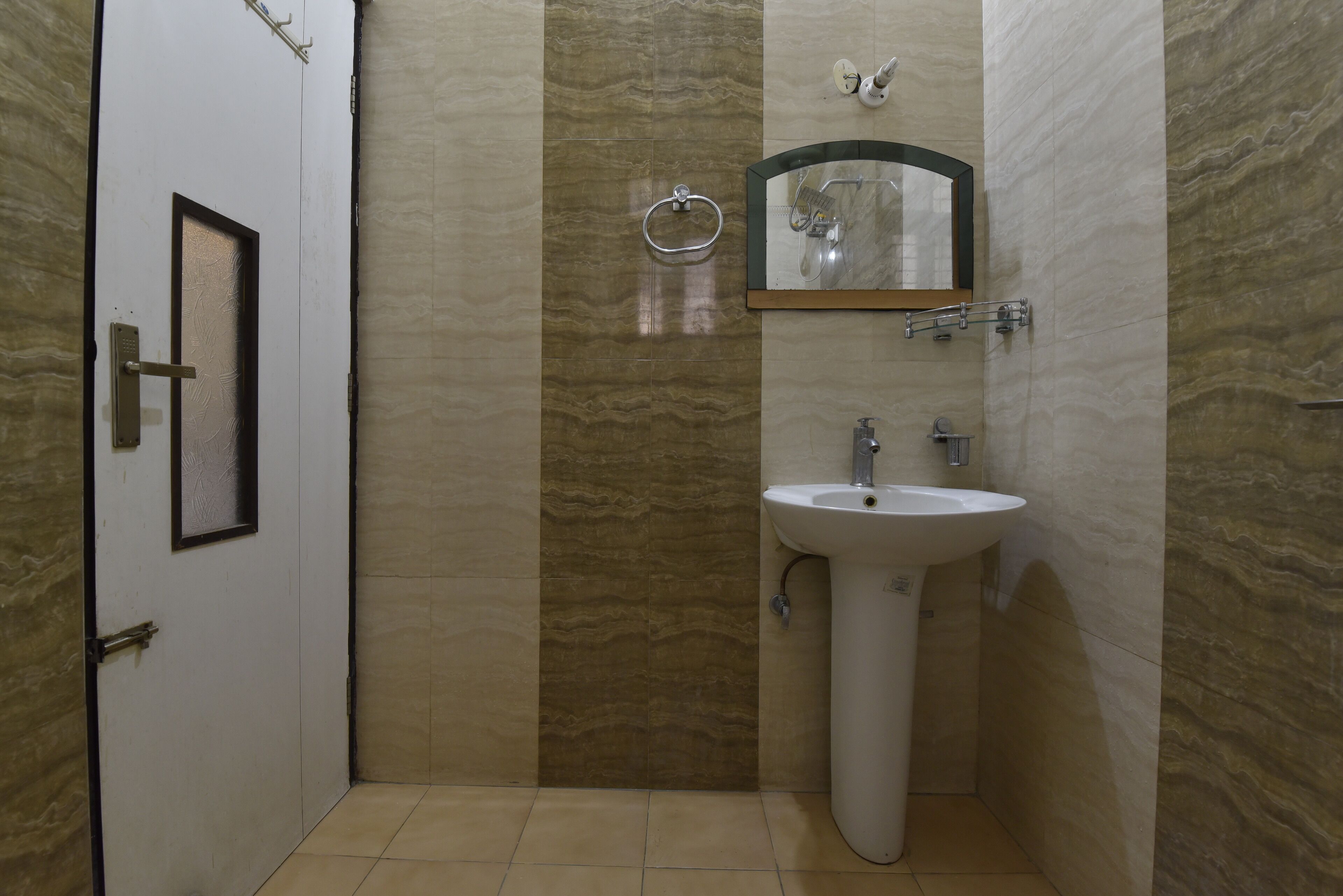 A bathroom with a white door, a sink, a mirror, and a towel rack.