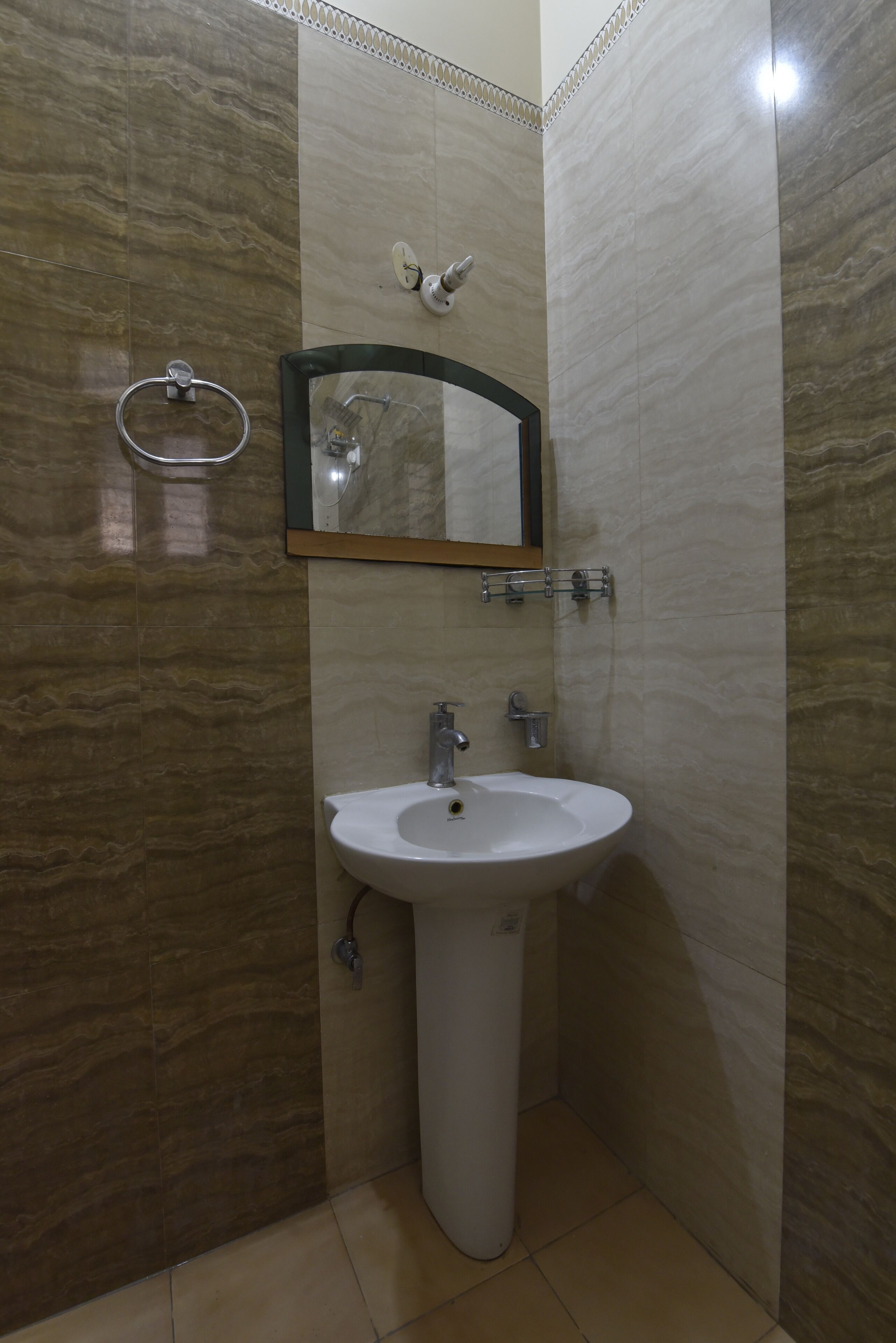 Un baño con lavamanos blanco, espejo y toallero.