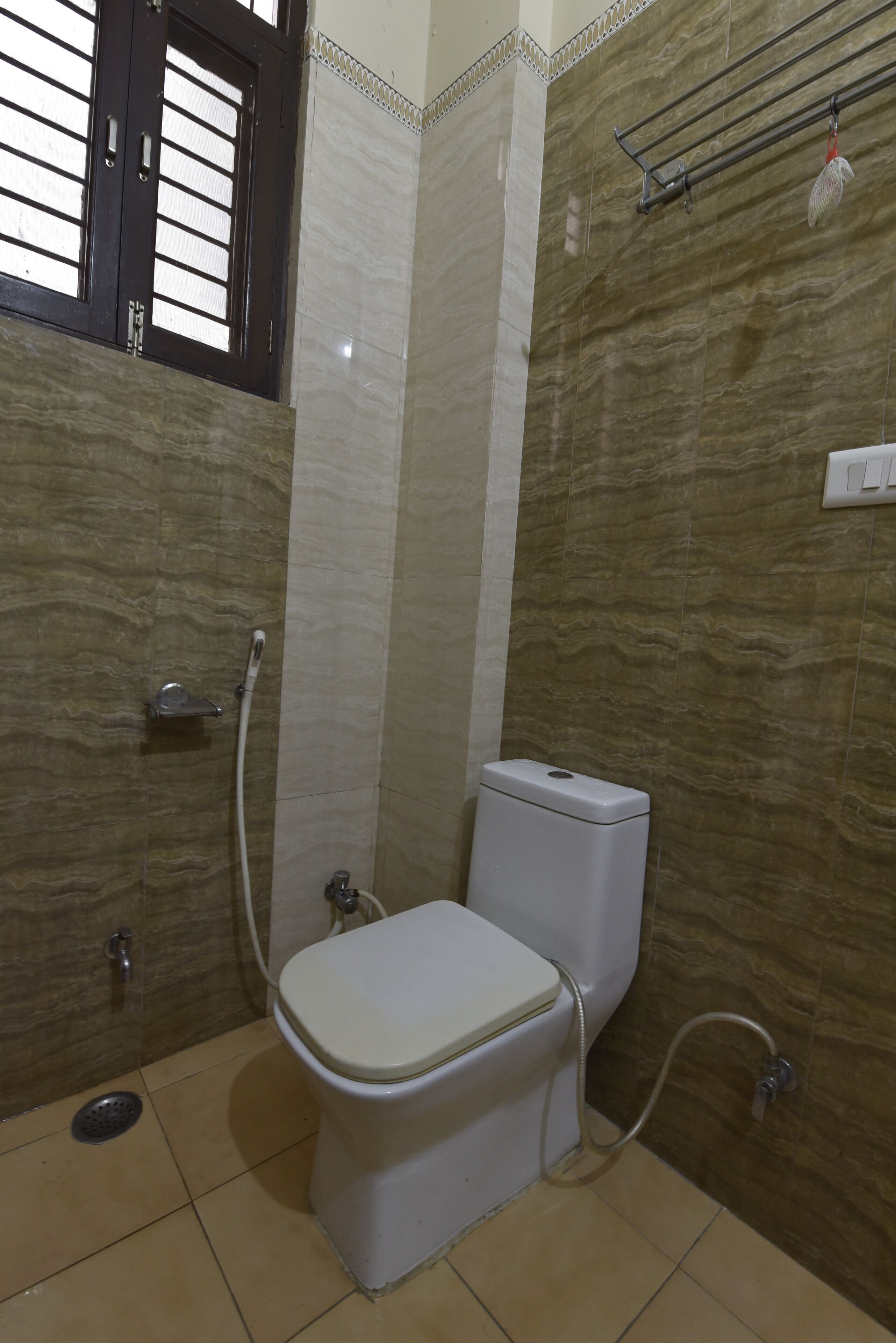 A bathroom with a toilet, shower, and a window with blinds.