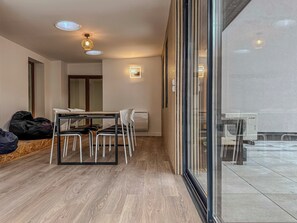 Ein moderner Essbereich mit Tisch und Stühlen, einer Deckenleuchte und Blick durch eine Glastür.