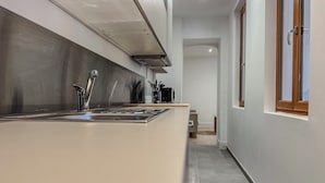 Ett modernt kök med en diskho i rostfritt stål, en inbyggd ugn och ett fönster med träramar.