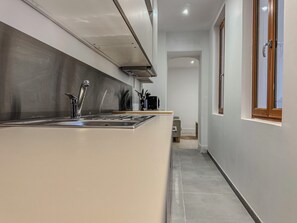 Eine moderne Küche mit Spüle aus Edelstahl, eingebautem Backofen und Fenster mit Holzrahmen.