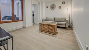 Ett modernt vardagsrum med en soffa, ett soffbord och ett stort fönster.