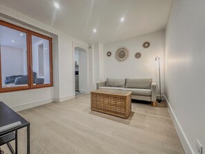 Ein modernes Wohnzimmer mit einer Couch, einem Couchtisch und einem großen Fenster.